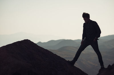 Full length of man standing on cliff against sky during sunset