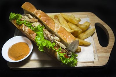 Sandwich with chicken and french fries on cutting board