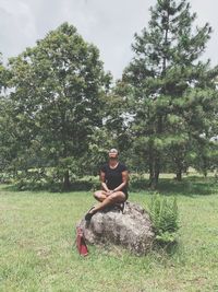 Young woman looking up while sitting on rock