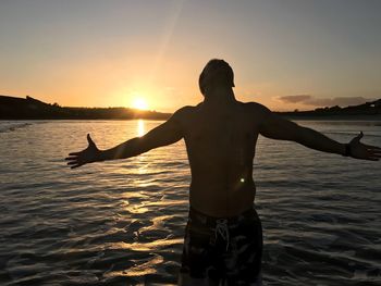 Silhouette man standing on beach during sunset