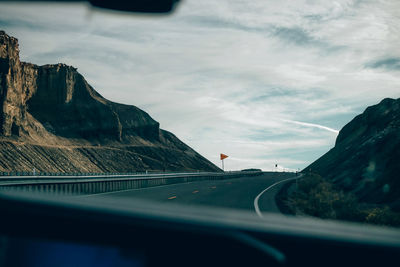 Road amidst mountains seen through car windshield