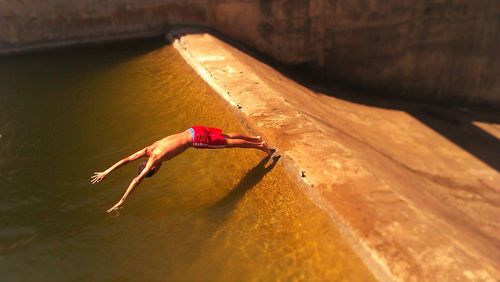 Full length of shirtless man diving into water at dam