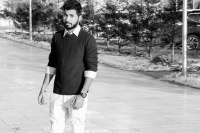 Portrait of young man standing on footpath