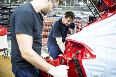 Two colleagues working in modern car factory