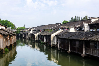 Houses by river and buildings against sky