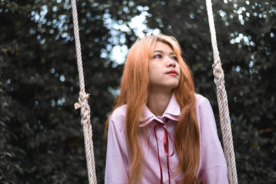 Low angle view of thoughtful young woman sitting on swing