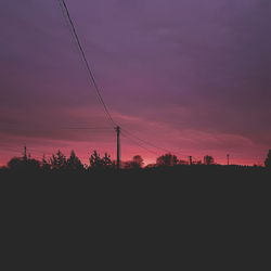 Silhouette electricity pylon against sky during sunset