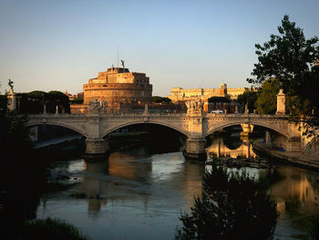 Arch bridge over river in city against sky