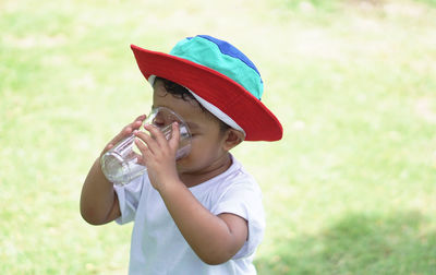 Baby boy drinking water while standing on land