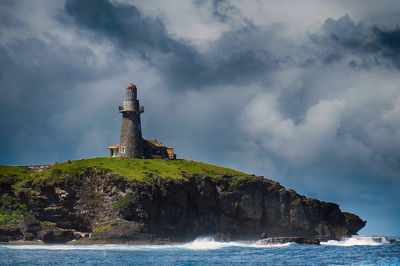 Lighthouse by sea against sky