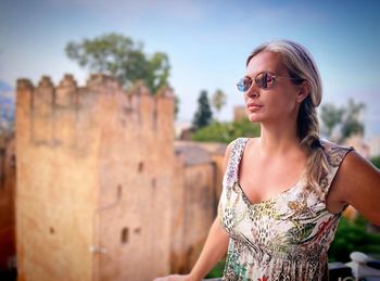 Portrait of young woman wearing sunglasses while standing outdoors