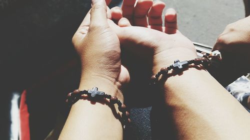 Cropped hands of couple wearing rosary bracelets