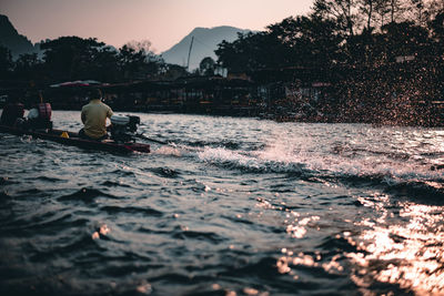 People in boat on river at sunset