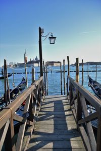 Pier over sea against clear blue sky