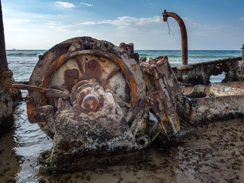 Rusty metal on beach against sky