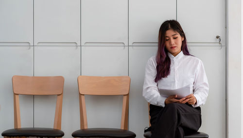 Young woman looking away while sitting on chair