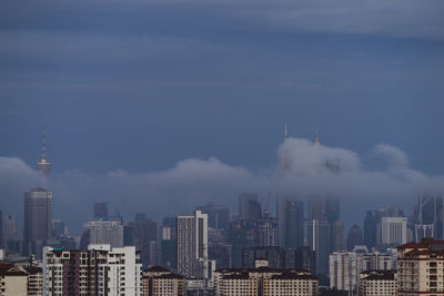 Buildings in city against cloudy sky