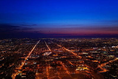 High angle view of illuminated city against sky at dusk