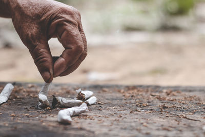 Cropped hands breaking cigarette outdoors