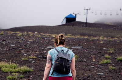 Rear view of female hiker walking on mountain against sky