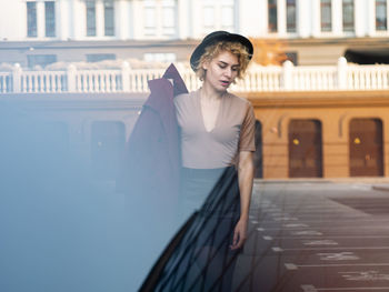 Portrait of young woman standing against building