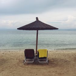 Chair on beach by sea against sky