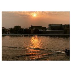 View of city at waterfront during sunset