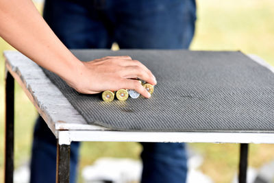 Midsection of woman holding bullets on table