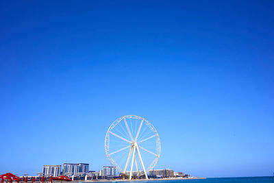 Ferris wheel and buildings against clear blue sky