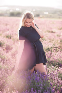 Happy pregnant woman standing on field