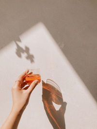 Close-up of hand holding drink against wall