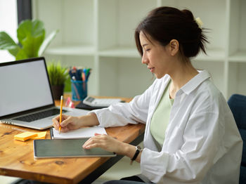 Woman using mobile phone while sitting on table