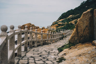 Footpath amidst rocky mountains against sky