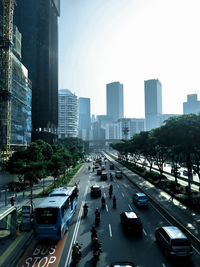 Vehicles on road amidst buildings in city against sky