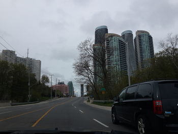 Cars on street in city against sky