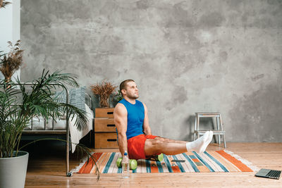 Sportsman with black hair shakes the press, does exercise for biceps, maintains balance on dumbbells