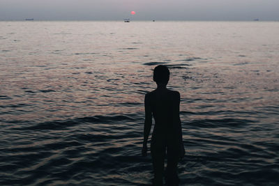 Rear view of woman standing in sea