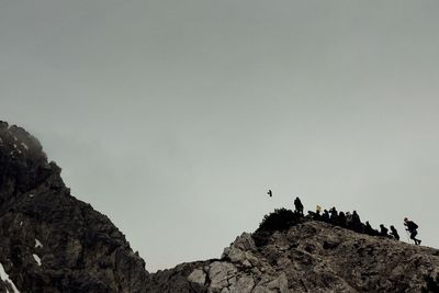 Low angle view of birds on mountain against sky