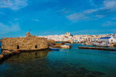 Buildings by sea against blue sky