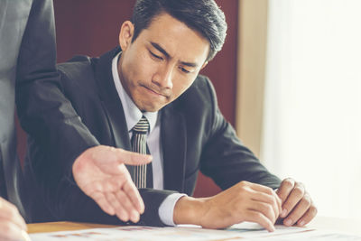 Midsection of businesswoman explaining to businessman in office