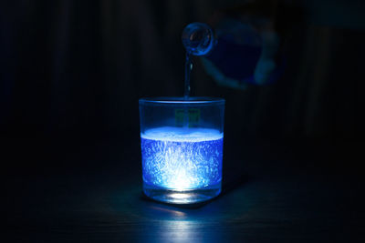 Close-up of water glass on table against black background