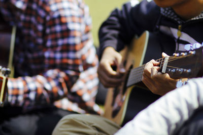 Two boys are sitting on the lawn playing guitar