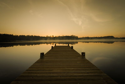 Pier over lake against sky during sunset