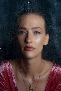 Close-up portrait of beautiful woman with blue eyes seen through window