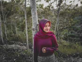 Portrait of smiling young woman standing on land