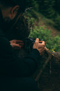 High angle view of man holding camera in forest