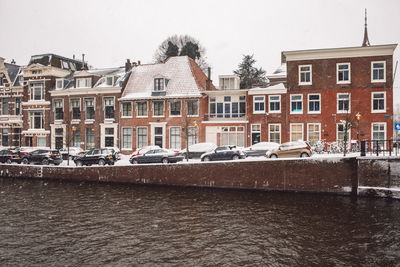 Houses by canal against buildings in city