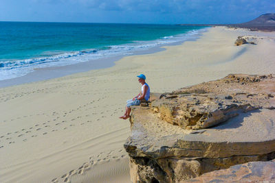 Man sitting on rock at beach