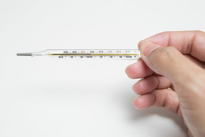 Close-up of hand holding paper over white background