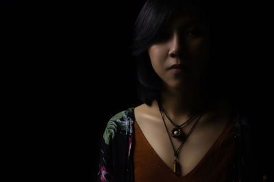 Portrait of young woman looking away over black background